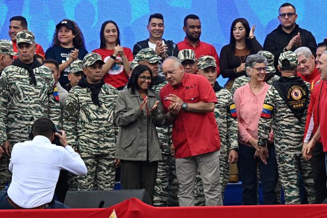 Venezuela's interim President Delcy Rodriguez (C, left) listens to Interior, Justice and Peace Minister Diosdado Cabello during a civil-military parade marking the 24th anniversary of late Venezuelan president Hugo Chavez's (1999-2013) return to power after a failed 2002 coup, in Caracas on April 13, 2026. (Photo by Federico PARRA / AFP)
