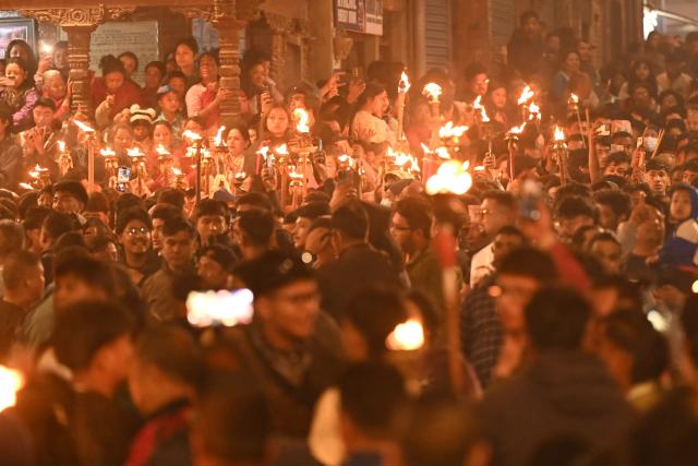 Hindu devotees carrying burning torches take part in a procession marking the Bisket Jatra festival to celebrate the Nepali New Year in Thimi on April 14, 2026. (Photo by PRAKASH MATHEMA / AFP)