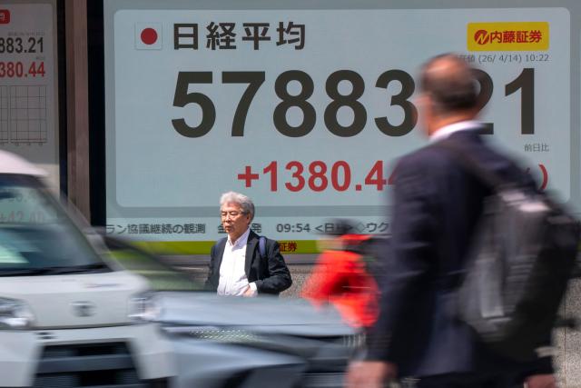 People walk past an electronic quotation board displaying the Nikkei Stock Average on the Tokyo Stock Exchange along a street in Tokyo on April 14, 2026. (Photo by Kazuhiro NOGI / AFP)