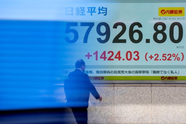 A man walks past an electronic quotation board displaying the Nikkei Stock Average on the Tokyo Stock Exchange along a street in Tokyo on April 14, 2026. (Photo by Kazuhiro NOGI / AFP)