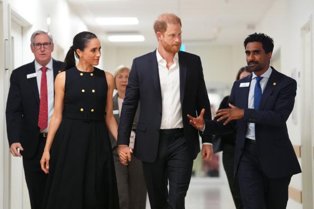 Britain's Prince Harry (C), Duke of Sussex, and his wife Meghan (L), speak with Kog Ravindran (R), Chief of Staff to the CEO & Executive Director Communications, during a visit at the Royal Children's Hospital in Melbourne on April 14, 2026. (Photo by Jonathan Brady / POOL / AFP)