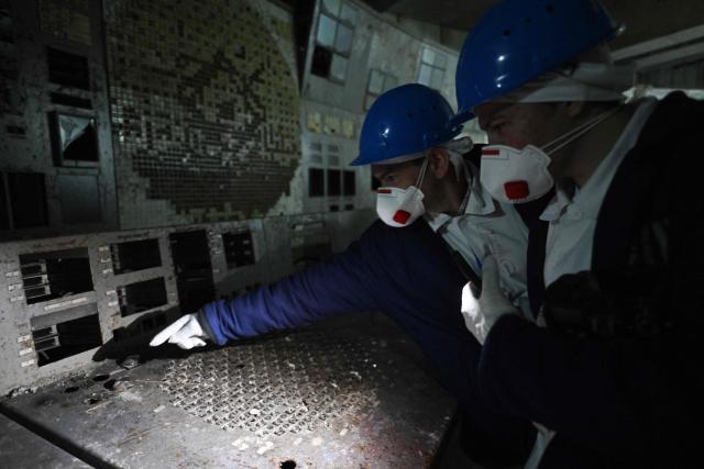Employees of the Chornobyl Nuclear Power Plant look at a panel in the control room of the destroyed 4th block of the plant on April 9, 2026, amid the Russian invasion of Ukraine. An uncontrolled collapse of the internal radiation shell at the defunct Chernobyl nuclear power station in Ukraine could increase the risk of radioactivity release in the environment, Greenpeace warned on April 14, 2026. (Photo by Genya SAVILOV / AFP)