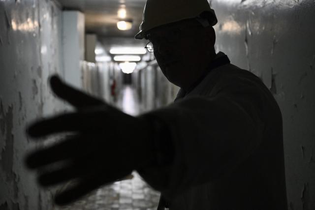 Chornobyl Nuclear Power Plant deputy technical director for radioactive waste management Oleksandr Skomarokhov, leads representatives of Greenpeace and media in the corridor among control rooms  of reactor 3 and 4 at the Chornobyl Nuclear Power Plant on April 9, 2026, amid the Russian invasion of Ukraine. An uncontrolled collapse of the internal radiation shell at the defunct Chernobyl nuclear power station in Ukraine could increase the risk of radioactivity release in the environment, Greenpeace warned on April 14, 2026. (Photo by Genya SAVILOV / AFP)