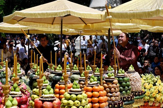 Cambodia's Deputy Prime Minister Hun Many (centre R) and Phnom Penh governor Khuong Sreng (centre L) light candles during Khmer New Year (Nokor Sankranta) celebrations at Wat Phnom in Phnom Penh on April 14, 2026. (Photo by TANG CHHIN Sothy / AFP)