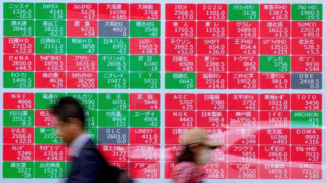 Passersby walk in front of an electronic quotation board displaying the Nikkei 225 stock prices on the Tokyo Stock Exchange along a street in Tokyo on April 14, 2026. (Photo by Kazuhiro NOGI / AFP)