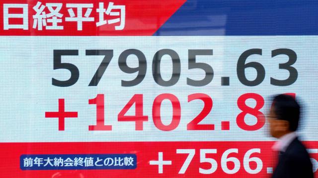 A man walks past an electronic quotation board displaying the Nikkei Stock Average on the Tokyo Stock Exchange along a street in Tokyo on April 14, 2026. (Photo by Kazuhiro NOGI / AFP)