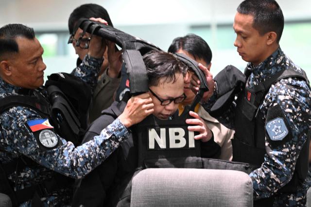 Members of the Bureau of jail management (L & R) remove the bullet proof vest of Ramil Madriaga (R) an alleged bagman of Philipine Vice-President Sara Duterte as he attends an impeachment hearing at the House of Representatives in Quezon City, suburban Manila on April 14, 2026. A Philippine congressional committee agreed overwhelmingly on March 4,to advance the impeachment case against Duterte, setting the stage for the poterntial vote that could decide her political future. (Photo by Ted ALJIBE / AFP)