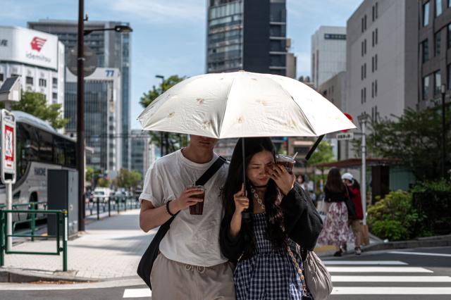 Pedestrians holding an umbrella walk along a street in Tokyo's Ginza district on April 14, 2026. (Photo by Philip FONG / AFP)