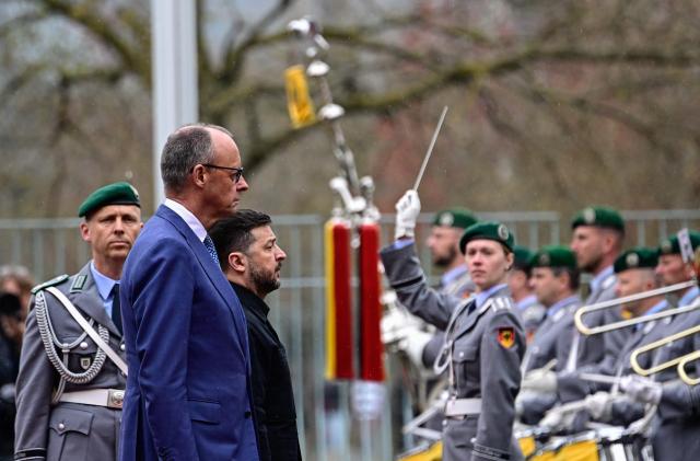 German Chancellor Friedrich Merz and Ukrainian President Volodymyr Zelensky review a military honour guard during a welcoming ceremony in the courtyard of the Chancellery in Berlin on April 14, 2026 prior to German-Ukrainian government consultations. The meeting comes as US-initiated peace talks between Russia and Ukraine have stalled, with Kyiv baulking at the idea it could cede territory to Russia. (Photo by Tobias SCHWARZ / AFP)