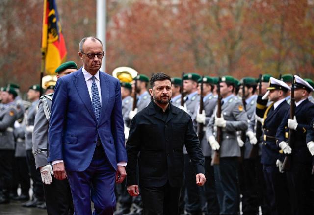 German Chancellor Friedrich Merz and Ukrainian President Volodymyr Zelensky review a military honour guard during a welcoming ceremony in the courtyard of the Chancellery in Berlin on April 14, 2026 prior to German-Ukrainian government consultations. The meeting comes as US-initiated peace talks between Russia and Ukraine have stalled, with Kyiv baulking at the idea it could cede territory to Russia. (Photo by Tobias SCHWARZ / AFP)