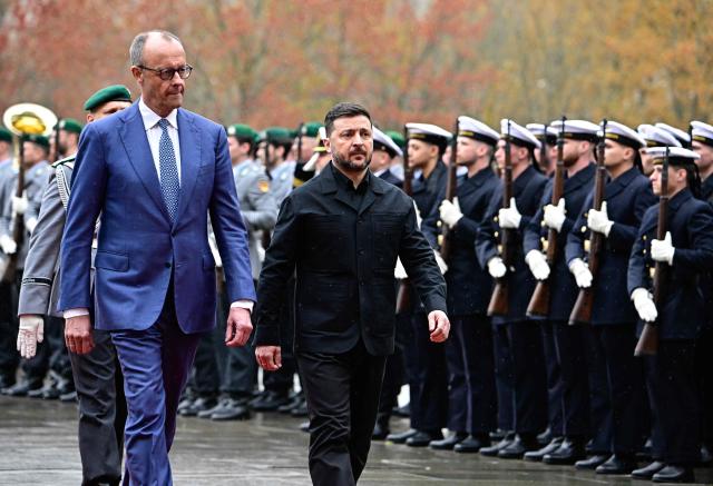 German Chancellor Friedrich Merz and Ukrainian President Volodymyr Zelensky review a military honour guard during a welcoming ceremony in the courtyard of the Chancellery in Berlin on April 14, 2026 prior to German-Ukrainian government consultations. The meeting comes as US-initiated peace talks between Russia and Ukraine have stalled, with Kyiv baulking at the idea it could cede territory to Russia. (Photo by Tobias SCHWARZ / AFP)