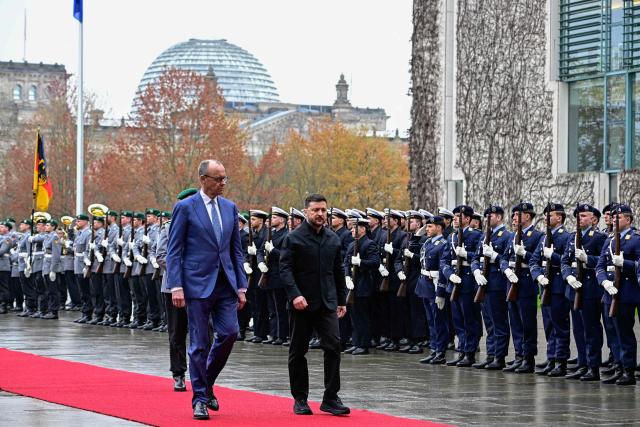 German Chancellor Friedrich Merz and Ukrainian President Volodymyr Zelensky review a military honour guard during a welcoming ceremony in the courtyard of the Chancellery in Berlin on April 14, 2026 prior to German-Ukrainian government consultations. The meeting comes as US-initiated peace talks between Russia and Ukraine have stalled, with Kyiv baulking at the idea it could cede territory to Russia. (Photo by Tobias SCHWARZ / AFP)