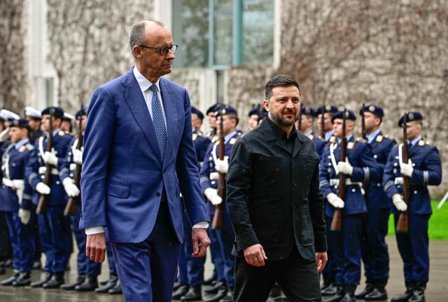 German Chancellor Friedrich Merz and Ukrainian President Volodymyr Zelensky review a military honour guard during a welcoming ceremony in the courtyard of the Chancellery in Berlin on April 14, 2026 prior to German-Ukrainian government consultations. The meeting comes as US-initiated peace talks between Russia and Ukraine have stalled, with Kyiv baulking at the idea it could cede territory to Russia. (Photo by Tobias SCHWARZ / AFP)