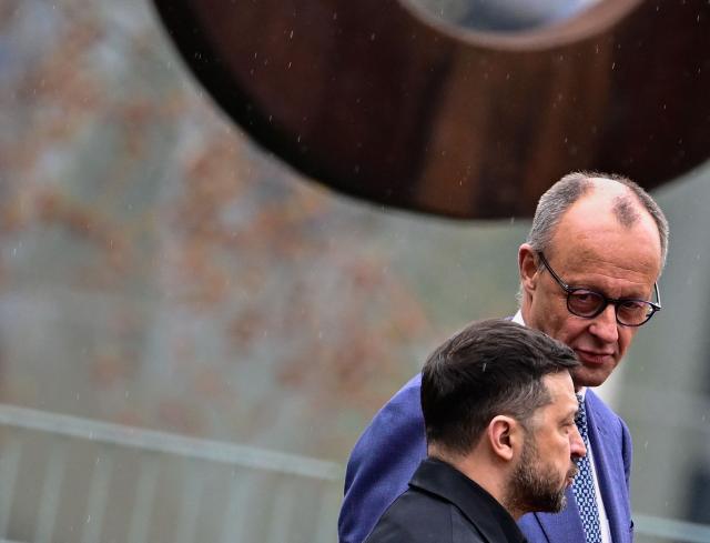 German Chancellor Friedrich Merz and Ukrainian President Volodymyr Zelensky listen to the national anthems during a welcoming ceremony in the courtyard of the Chancellery in Berlin on April 14, 2026 prior to German-Ukrainian government consultations. The meeting comes as US-initiated peace talks between Russia and Ukraine have stalled, with Kyiv baulking at the idea it could cede territory to Russia. (Photo by Tobias SCHWARZ / AFP)