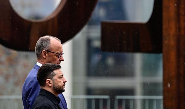 German Chancellor Friedrich Merz and Ukrainian President Volodymyr Zelensky listen to the national anthems during a welcoming ceremony in the courtyard of the Chancellery in Berlin on April 14, 2026 prior to German-Ukrainian government consultations. The meeting comes as US-initiated peace talks between Russia and Ukraine have stalled, with Kyiv baulking at the idea it could cede territory to Russia. (Photo by Tobias SCHWARZ / AFP)