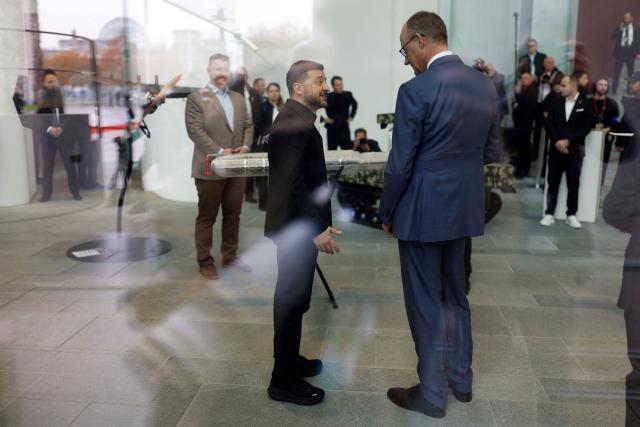 German Chancellor Friedrich Merz (R) and Ukrainian President Volodymyr Zelensky are seen through a window during a presentation of drones made in German-Ukrainian cooperation during a visit at the Chancellery in Berlin on April 14, 2026 prior to German-Ukrainian government consultations. The meeting comes as US-initiated peace talks between Russia and Ukraine have stalled, with Kyiv baulking at the idea it could cede territory to Russia. (Photo by Odd ANDERSEN / AFP)