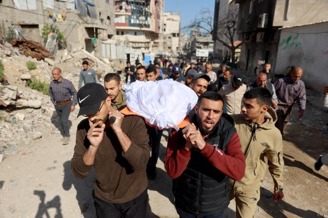 Palestinian mourners carry the shrouded body of Islam Quneita, a writer and managing editor for the website “Palestine Now,” who, according to medics, was killed in an Israeli strike the day before, past destroyed buildings and tents used as homes by displaced families during his funeral in Gaza City on April 14, 2026. Gaza is still reeling from more than two years of war between Israel and Hamas, sparked by the militant group's October 7, 2023, attack on Israel. (Photo by Omar AL-QATTAA / AFP)