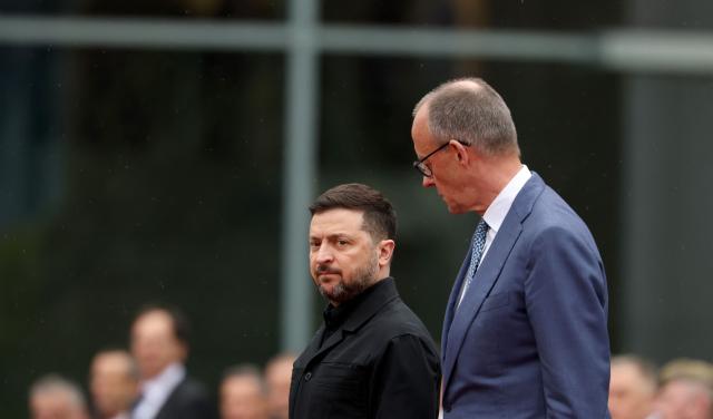 German Chancellor Friedrich Merz (R) and Ukrainian President Volodymyr Zelensky review a military honor guard during a welcome ceremony at the Chancellery in Berlin on April 14, 2026 prior to German-Ukrainian government consultations. The meeting comes as US-initiated peace talks between Russia and Ukraine have stalled, with Kyiv baulking at the idea it could cede territory to Russia. (Photo by Odd ANDERSEN / AFP)