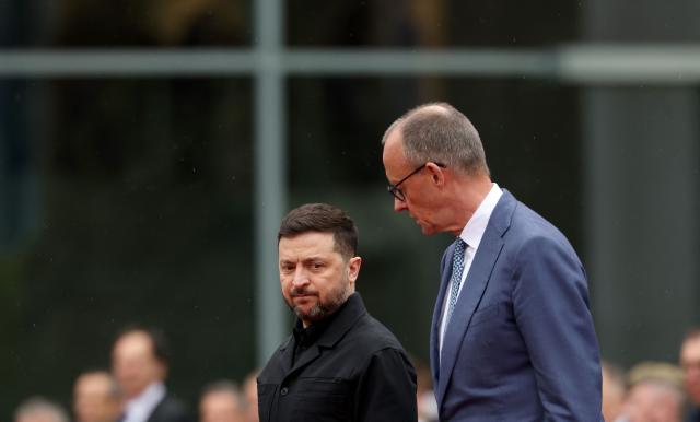 German Chancellor Friedrich Merz (R) and Ukrainian President Volodymyr Zelensky review a military honor guard during a welcome ceremony at the Chancellery in Berlin on April 14, 2026 prior to German-Ukrainian government consultations. The meeting comes as US-initiated peace talks between Russia and Ukraine have stalled, with Kyiv baulking at the idea it could cede territory to Russia. (Photo by Odd ANDERSEN / AFP)