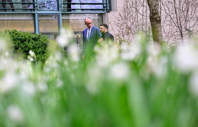 German Chancellor Friedrich Merz and Ukrainian President Volodymyr Zelensky walk in the garden in the backyard of the Chancellery in Berlin on April 14, 2026 prior to German-Ukrainian government consultations. The meeting comes as US-initiated peace talks between Russia and Ukraine have stalled, with Kyiv baulking at the idea it could cede territory to Russia. (Photo by Tobias SCHWARZ / AFP)