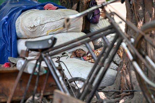 A worker rests during a break in New Delhi on April 14, 2026. (Photo by Sajjad HUSSAIN / AFP)