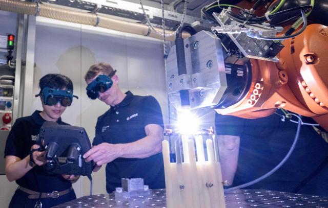 Employees of Bosch Manufacturing Solutions control copper welding in the eDrive Lab in Stuttgart, southern Germany, on April 14, 2026. The eDrive Lab optimizes the manufacturing steps for serial production of electric drives. Bosch will hold its annual press conference on April 16, 2026. (Photo by THOMAS KIENZLE / AFP)