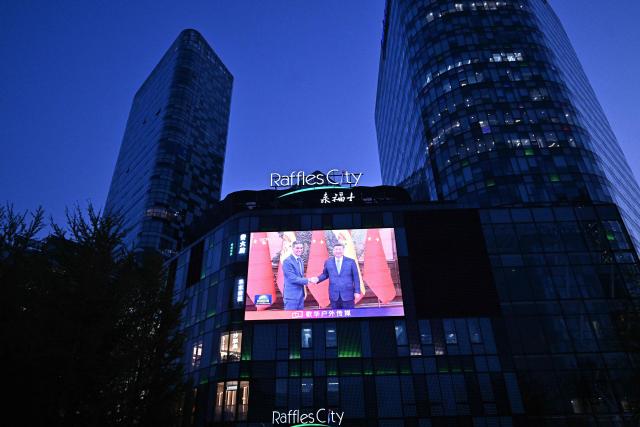 News footage on a giant screen outside a shopping mall shows China's President Xi Jinping (R) meeting with Spain's Prime Minister Pedro Sanchez in Beijing on April 14, 2026. (Photo by Pedro Pardo / AFP)