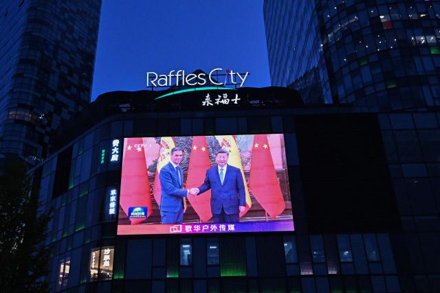 News footage on a giant screen outside a shopping mall shows China's President Xi Jinping (R) meeting with Spain's Prime Minister Pedro Sanchez in Beijing on April 14, 2026. (Photo by Pedro PARDO / AFP)