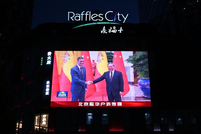 News footage on a giant screen outside a shopping mall shows China's Premier Li Qiang (R) meeting with Spain's Prime Minister Pedro Sanchez in Beijing on April 14, 2026. (Photo by Pedro PARDO / AFP)