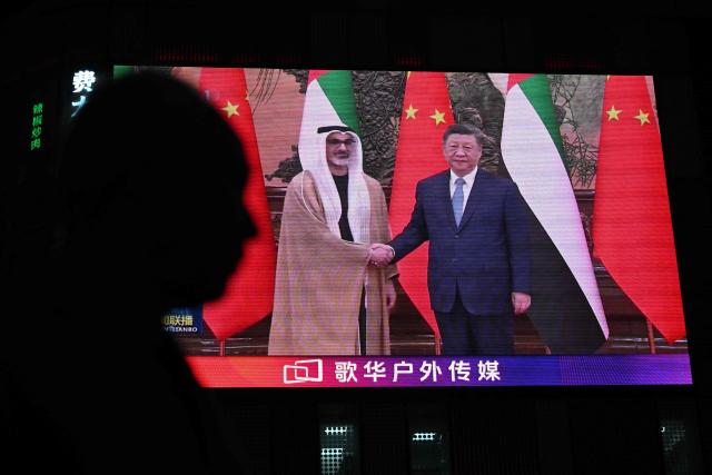 News footage on a giant screen outside a shopping mall shows China's President Xi Jinping (R) meeting with Abu Dhabi's Crown Prince Sheikh Khaled bin Mohamed bin Zayed Al Nahyan in Beijing on April 14, 2026. (Photo by Pedro PARDO / AFP)