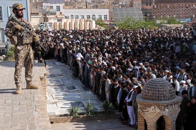 A Taliban security persnnel stands guard as mourners offer funeral prayers for victims killed in an attack by unidentified gunmen in Herat on April 14, 2026 following a shooting incident on April 11. The death toll from a shooting in western Afghanistan hit 11, the provincial authority said after gunmen targeted civilians at a picnic spot in Herat. (Photo by Mohsen KARIMI / AFP)