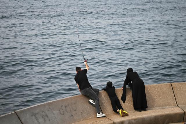 A man fishes with his family near an unofficial camp for displaced people in Beirut's waterfront area on April 14, 2026. Israel said it was open to peace with Lebanon ahead of the first direct talks in decades between the neighbours on April 14, but that Hezbollah remained the "problem" blocking an agreement on ending fighting. (Photo by Joseph EID / AFP)