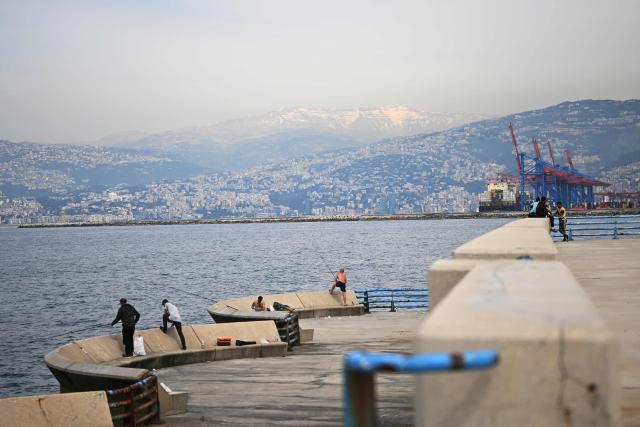 Men fish near an unofficial camp for displaced people in Beirut's waterfront area on April 14, 2026. Israel said it was open to peace with Lebanon ahead of the first direct talks in decades between the neighbours on April 14, but that Hezbollah remained the "problem" blocking an agreement on ending fighting. (Photo by Joseph EID / AFP)