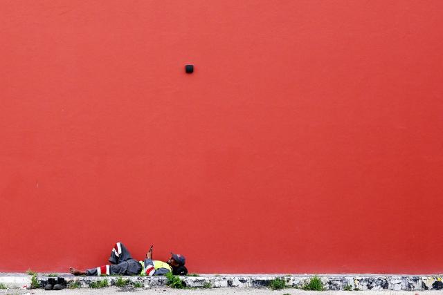 TOPSHOT - A sanitation worker rests in the shade of a building near an unofficial camp for displaced people in Beirut's waterfront area on April 14, 2026. Israel said it was open to peace with Lebanon ahead of the first direct talks in decades between the neighbours on April 14, but that Hezbollah remained the "problem" blocking an agreement on ending fighting. (Photo by Joseph EID / AFP)