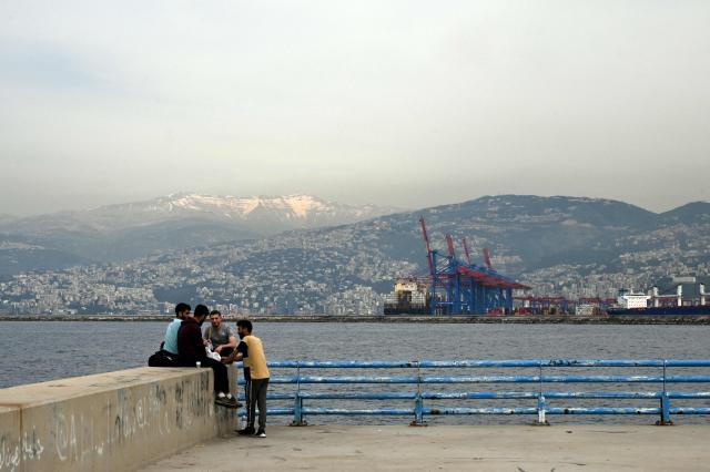 Men smoke a waterpipe as they sit by the sea near an unofficial camp for displaced people in Beirut's waterfront area on April 14, 2026. Israel said it was open to peace with Lebanon ahead of the first direct talks in decades between the neighbours on April 14, but that Hezbollah remained the "problem" blocking an agreement on ending fighting. (Photo by Joseph EID / AFP)