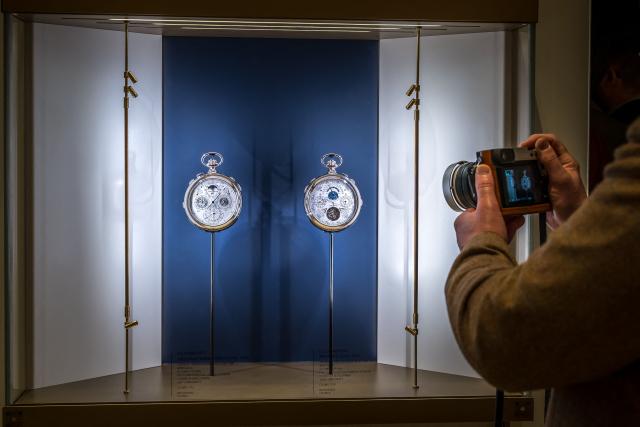 A visitor takes a picture at the booth of Swiss luxury watch and clock manufacturer Vacheron Constantin owned by the Richemont group during the opening day of the "Watches and Wonders Geneva" luxury watch fair, in Geneva on April 14, 2026. The Geneva watch fair opened on April 14 and will be taken as a barometer of how the Middle East war is affecting the luxury goods sector. The Watches and Wonders salon -- the industry's biggest annual event -- sees 65 major watch brands, including Rolex, Patek Philippe, Cartier and Bulgari, display their latest creations until April 20. (Photo by Fabrice COFFRINI / AFP)