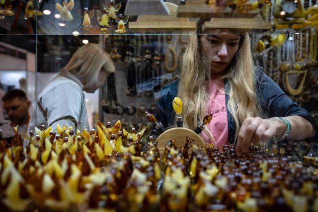 A woman arranges figurines made from Baltic amber in a display case at the Amberif fair in Gdansk on March 27, 2026. Around 200 exhibitors take part in this year’s Amberif, a fair held annually in Gdansk where entrepreneurs, craftsmen and artists from all over the world who work with amber can sell or buy amber, establish new contracts or simply showcase their offerings. (Photo by Wojtek RADWANSKI / AFP)