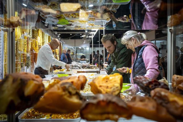 Customers look at a selection of amber at a vendor's stall at the Amberif fair in Gdansk, on March 26, 2026. Around 200 exhibitors take part in this year’s Amberif, a fair held annually in Gdansk where entrepreneurs, craftsmen and artists from all over the world who work with amber can sell or buy amber, establish new contracts or simply showcase their offerings. (Photo by Wojtek RADWANSKI / AFP)
