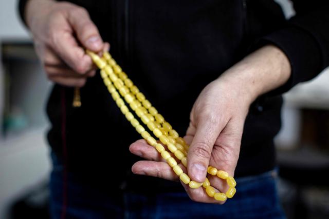 Michal Kosior, gemologist, amber specialist and founder of "Amber Expert", presents prayer beads made with fake amber (L) and real Baltic amber (R) in his laboratory in Gdansk, northern Poland, on March 11, 2026. Formed some 40 million years ago from conifer resins, amber often contains air bubbles, plant fragments or insects trapped before fossilisation, granting each piece a unique "fingerprint". In Gdansk itself, workshops, shops and stalls dedicated to amber abound on every corner of the historic centre, each attracting flocks of tourists. (Photo by Wojtek RADWANSKI / AFP)