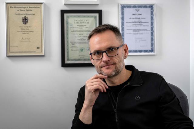 Michal Kosior, gemologist, amber specialist and founder of "Amber Expert", poses for photos in front of several certificates in his laboratory in Gdansk, northern Poland, on March 11, 2026. Formed some 40 million years ago from conifer resins, amber often contains air bubbles, plant fragments or insects trapped before fossilisation, granting each piece a unique "fingerprint". In Gdansk itself, workshops, shops and stalls dedicated to amber abound on every corner of the historic centre, each attracting flocks of tourists. (Photo by Wojtek RADWANSKI / AFP)