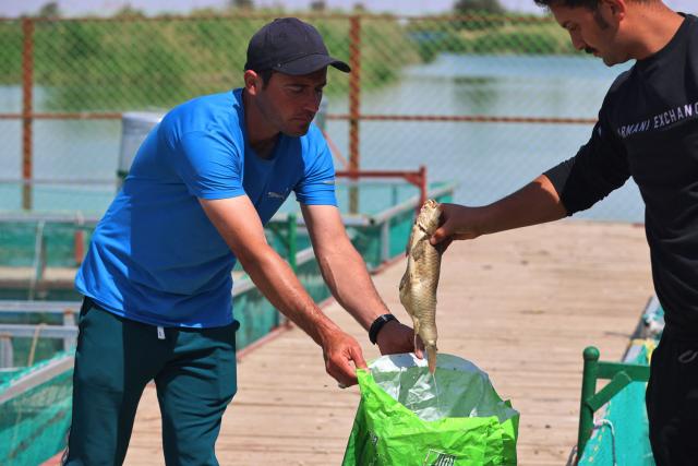 Iraqi fish farmers clean tanks of dead fish at a farm in the town of al-Numaniyah, near the city of Kut in southern Iraq, on April 14, 2026. Thousands of fish died last week in eastern Iraq in polluted water from sewage in the Tigris River, which caused huge losses to fish farmers. Heavy rains and floods that swept through Iraq last week pushed sewage from the Diyala River into the Tigris River, polluting the river's waters in southern Iraq. (Photo by AHMAD AL-RUBAYE / AFP)