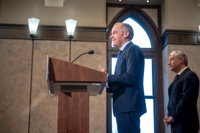 Canadian Prime Minister Mark Carney speaks alongside Canadian Finance Minister Francois-Philippe Champagne (R) during a press conference at the West Block on Parliament Hill in Ottawa, Ontario, Canada, on April 14, 2026. Carney's Liberal party secured a majority in Canada's parliament on April 13 after winning all three by-election seats up for grabs, boosting his Liberals as they work to bolster a country shaken by threats from the United States. (Photo by ANDREJ IVANOV / AFP)