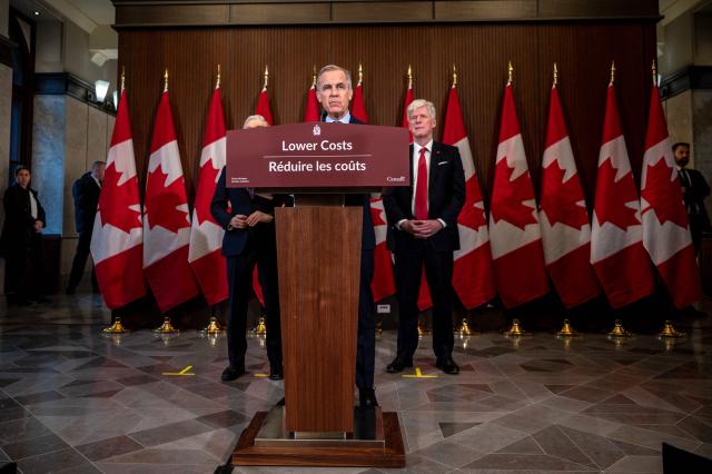 Canadian Prime Minister Mark Carney (C), alongside Canadian Finance Minister Francois-Philippe Champagne (L) and Canadian Minister of Energy and Natural Resources Tim Hodgson (R), speaks during a press conference at the West Block on Parliament Hill in Ottawa, Ontario, Canada, on April 14, 2026. Carney's Liberal party secured a majority in Canada's parliament on April 13 after winning all three by-election seats up for grabs, boosting his Liberals as they work to bolster a country shaken by threats from the United States. (Photo by ANDREJ IVANOV / AFP)