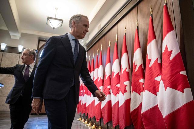 Canadian Prime Minister Mark Carney (R) and Canadian Finance Minister Francois-Philippe Champagne (L) depart at the end of a press conference at the West Block on Parliament Hill in Ottawa, Ontario, Canada, on April 14, 2026. Carney's Liberal party secured a majority in Canada's parliament on April 13 after winning all three by-election seats up for grabs, boosting his Liberals as they work to bolster a country shaken by threats from the United States. (Photo by ANDREJ IVANOV / AFP)