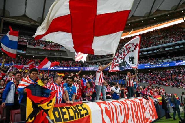 Atletico Madrid supporters wave flags before the UEFA Champions League quarter final second leg football match between Club Atletico de Madrid and FC Barcelona at Metropolitano Stadium in Madrid on April 14, 2026. (Photo by Javier SORIANO / AFP)
