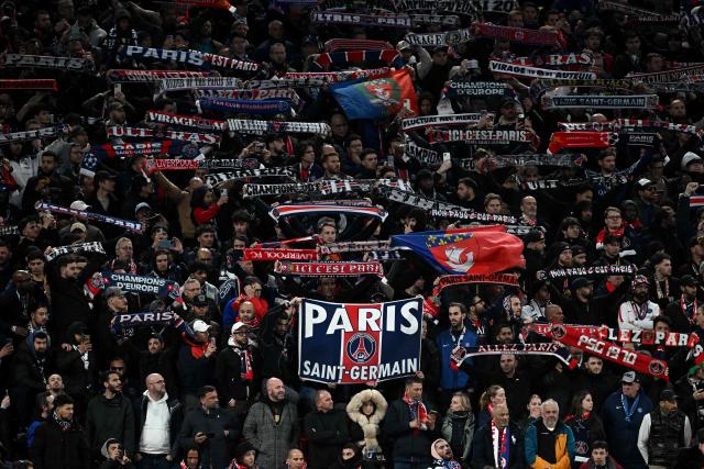 PSG fans hold scarves aloft during the UEFA Champions League quarter final, second-leg football match between Liverpool and Paris Saint-Germain at Anfield in Liverpool, north west England on April 14, 2026. (Photo by Paul ELLIS / AFP)