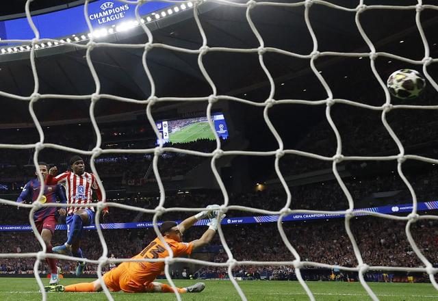 Atletico Madrid's English forward #22 Ademola Lookman scores his team's first goal in spite of Barcelona's Spanish goalkeeper #13 Joan Garcia during the UEFA Champions League quarter final second leg football match between Club Atletico de Madrid and FC Barcelona at Metropolitano Stadium in Madrid on April 14, 2026. (Photo by Oscar DEL POZO / AFP)