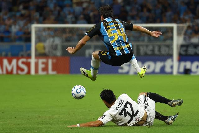 Gremio's defender #54 Pedro Gabriel and Deportivo Riestra's forward #32 Gonzalo Flores fight for the ball during the Copa Sudamericana group stage football match between Brazil's Gremio and Argentina's Deportivo Riestra at the Arena do Gremio stadium in Porto Alegre, state of Rio Grande do Sul, Brazil, on April 14, 2026. (Photo by SILVIO AVILA / AFP)