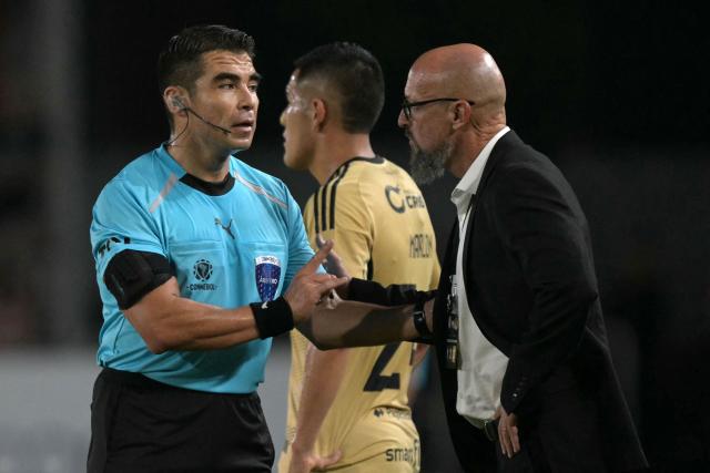 Chilean referee Jose Cabero talks to Cusco's Uruguayan head coach Alejandro Orfila during the Copa Libertadores group stage football match between Argentina's Estudiantes de La Plata and Peru's Cusco FC at Jorge Luis Hirschi stadium in La Plata, Buenos Aires province, Argentina on April 14, 2026. (Photo by JUAN MABROMATA / AFP)