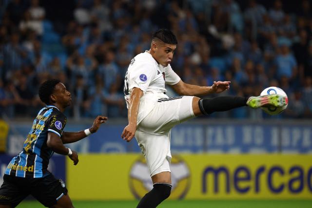 Deportivo Riestra's forward #40 Gabriel Obredor kicks the ball past Gremio's midfielder #37 Gabriel Mec during the Copa Sudamericana group stage football match between Brazil's Gremio and Argentina's Deportivo Riestra at the Arena do Gremio stadium in Porto Alegre, state of Rio Grande do Sul, Brazil, on April 14, 2026. (Photo by SILVIO AVILA / AFP)